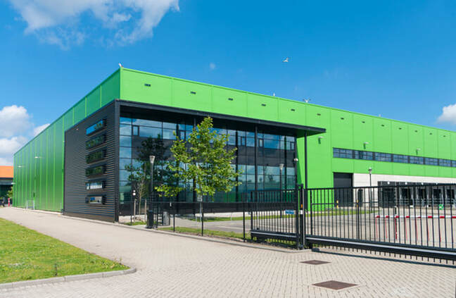 Picture of a green commercial building with a fence and security gate in front of it