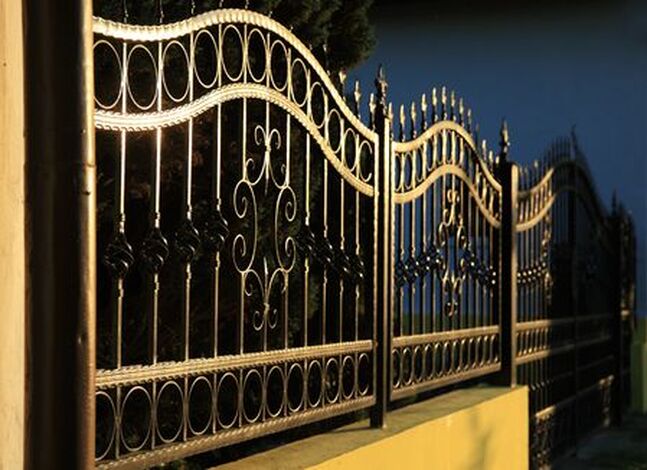 Picture of a black wrought iron fence in the night