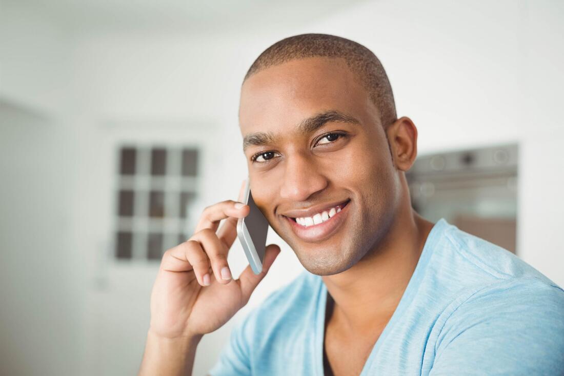 Picture of an African-American man wearing a blue shirt talking over the phone